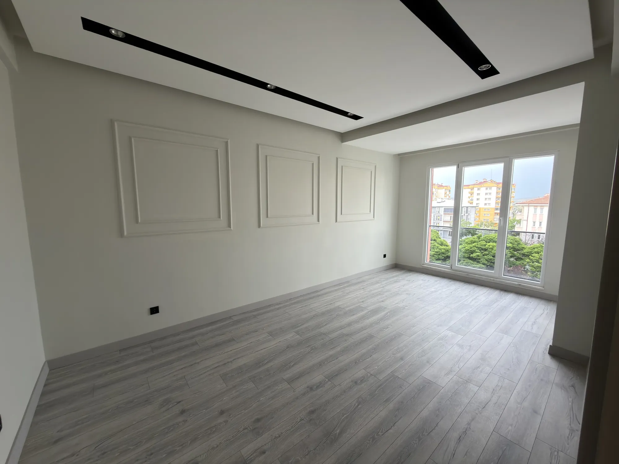 Yavuzhan Apt. A Blok — teslim edilen 2+1 dairenin salonu, duvar çıtaları ve geniş pencere